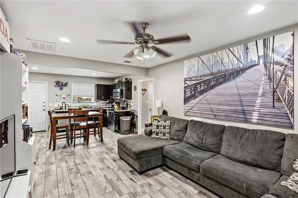 a living room with furniture kitchen view and a large window