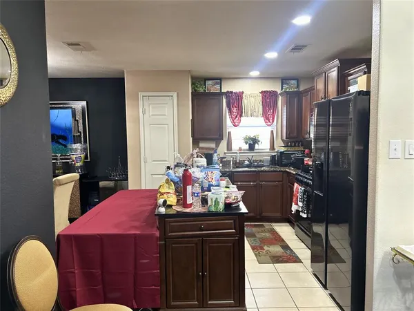 a kitchen with a sink dishwasher a refrigerator and a dining table with wooden cabinet