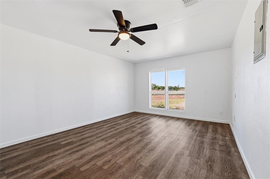 100 West Dilworth Road Italy, TX 76651 - Photo 20 of 38 an empty room with wooden floor a ceiling fan and windows