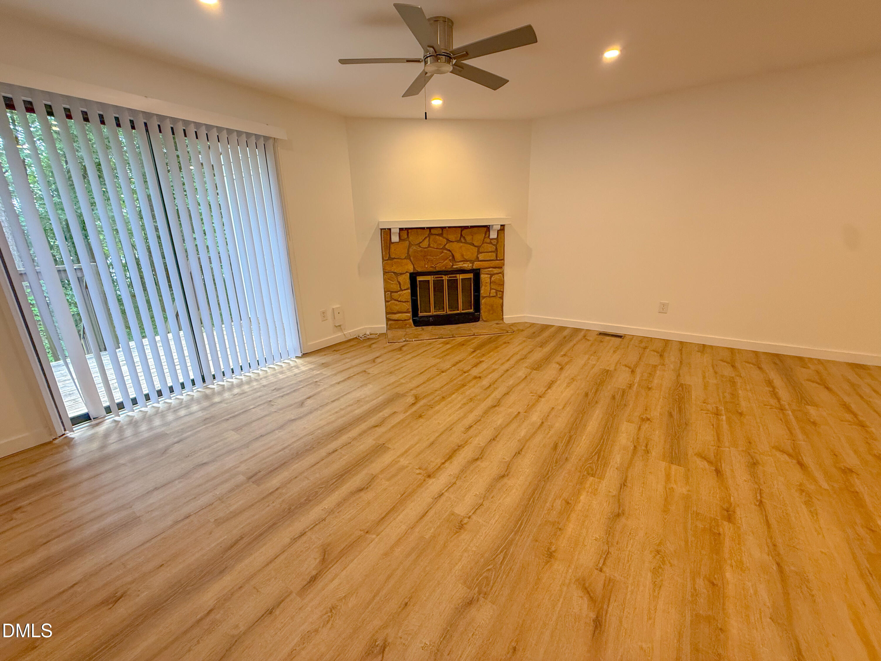 4247 The Oaks Drive Raleigh, NC 27606 - Photo 4 of 21 an empty room with wooden floor fireplace and windows