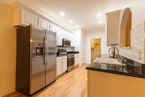 a kitchen with stainless steel appliances granite countertop a refrigerator a stove and a sink with wooden floor