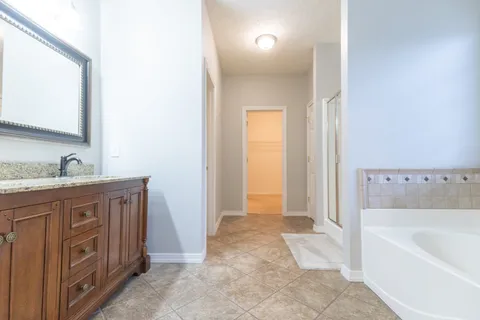 a spacious bathroom with a granite countertop sink a mirror and a bathtub