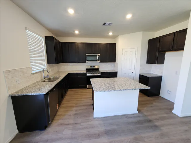 a large kitchen with stainless steel appliances kitchen island granite countertop a table and chairs