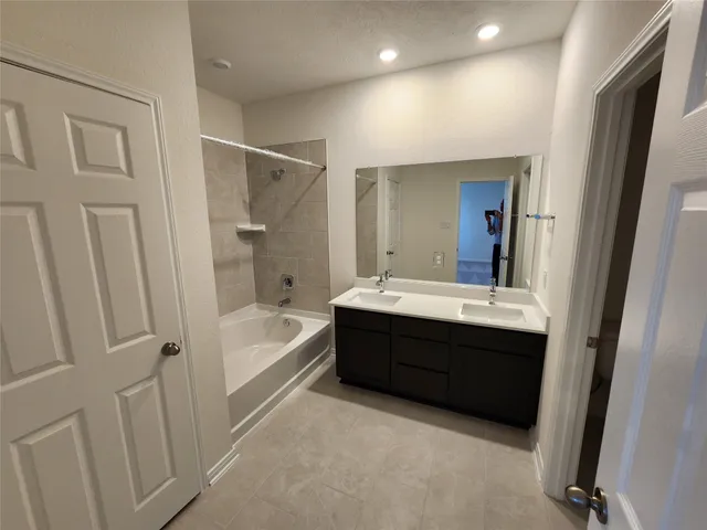 a bathroom with a tub sink shower and mirror