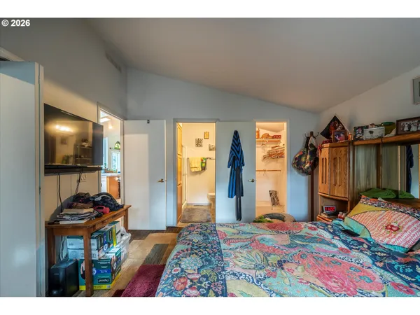 a bedroom with a bed and a flat tv screen on dresser