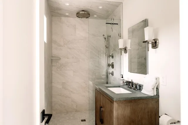 a bathroom with a sink shower and a mirror