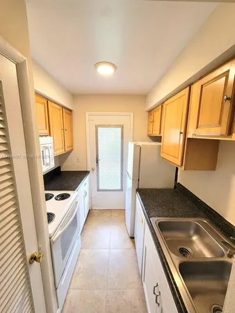 a kitchen with granite countertop a sink stove and refrigerator