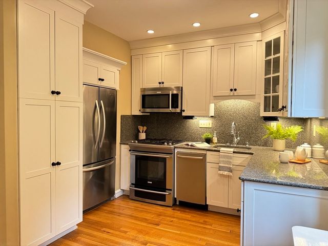 a kitchen with stainless steel appliances granite countertop a refrigerator a stove a sink and a microwave