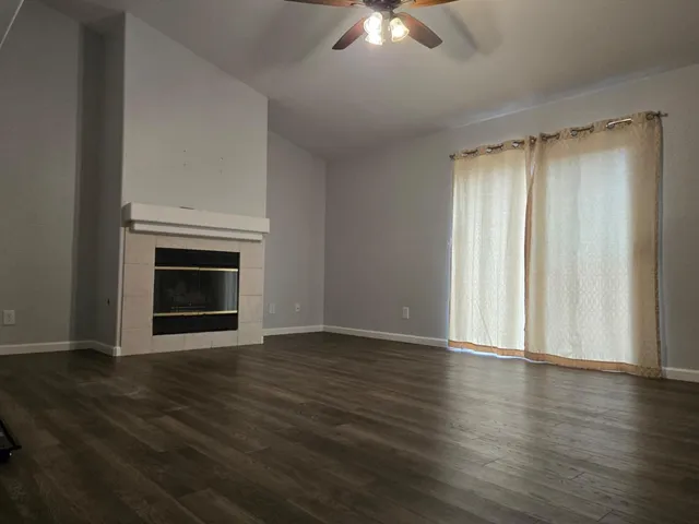 an empty room with wooden floor fireplace and windows
