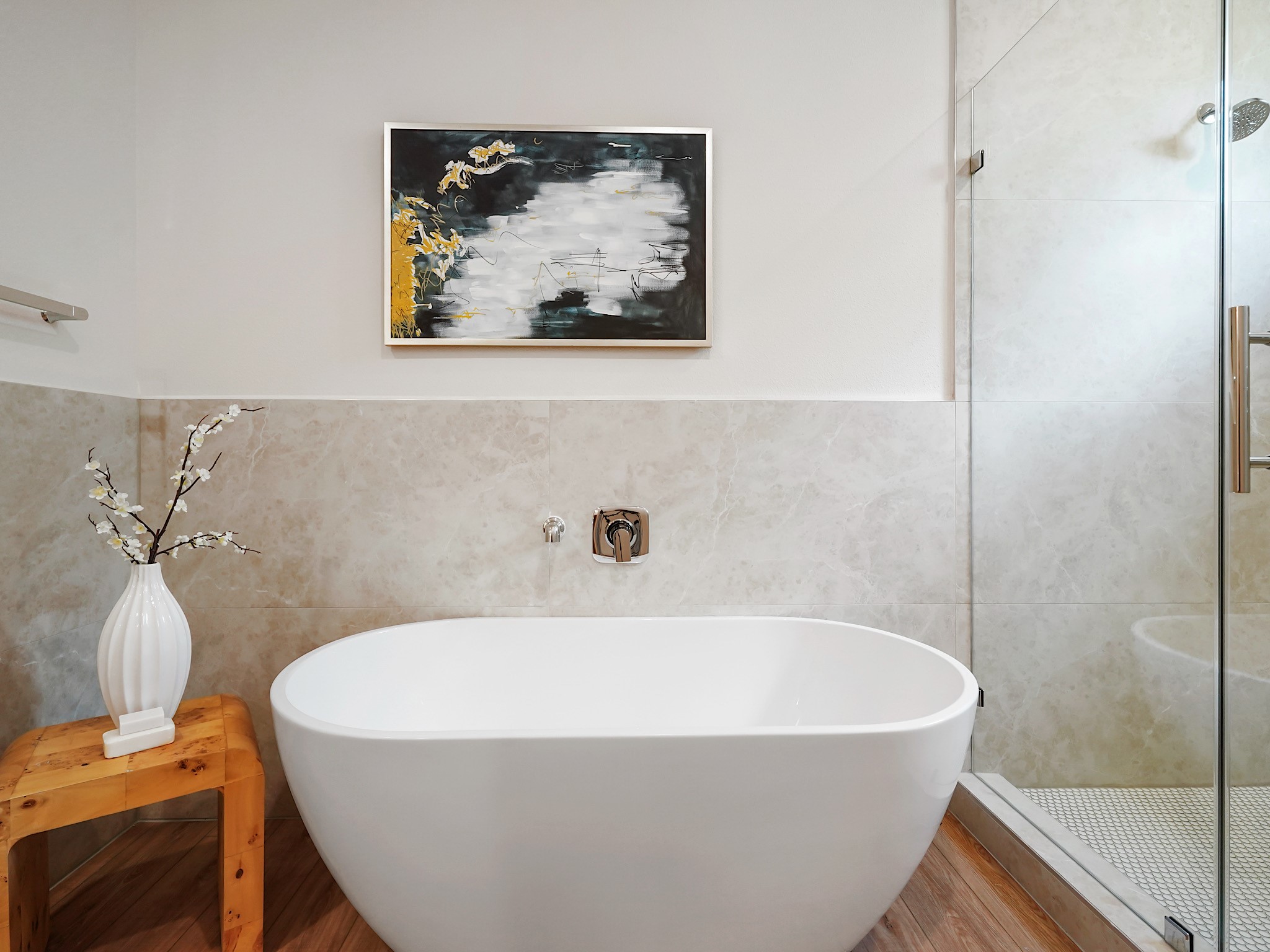 861 Rachel Street, Unit E Houston, TX 77091 - Photo 17 of 29 This bathroom features a modern freestanding tub, a glass-enclosed shower, and elegant tile work. A wooden stool with a vase adds warmth, while a contemporary artwork enhances the space's stylish appeal.