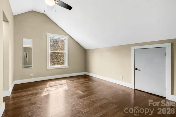 an empty room with wooden floor and a ceiling fan