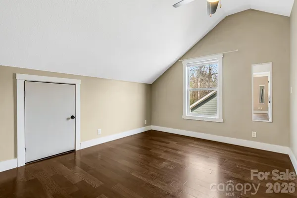 a view of an empty room with a window and wooden floor