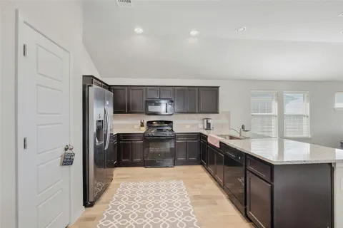 a large kitchen with stainless steel appliances kitchen island granite countertop a refrigerator and a sink