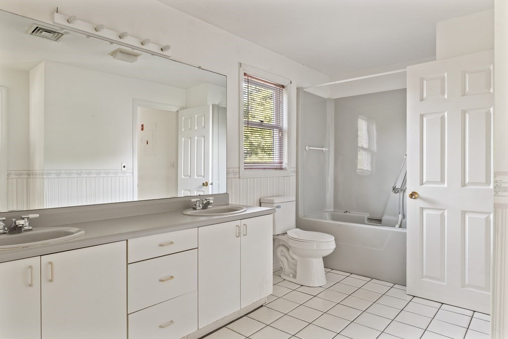29 Ledgebrook Drive, Unit 29 Blackstone, MA 01504 - Photo 19 of 38 a bathroom with a double vanity sink a toilet a mirror and shower