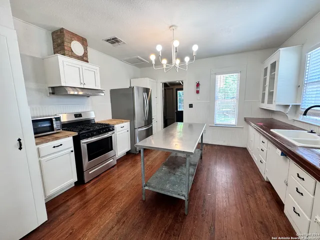a large kitchen with cabinets wooden floor and stainless steel appliances