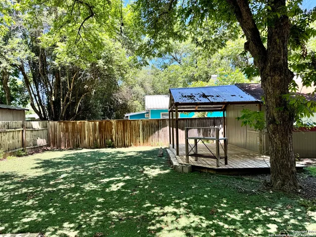 a view of a yard with wooden fence and a large tree