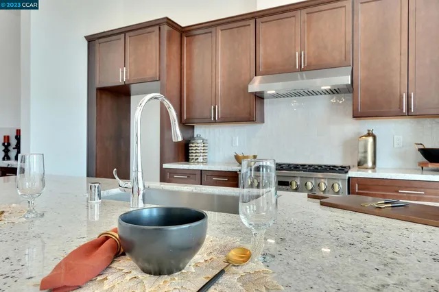 a kitchen with stainless steel appliances granite countertop a sink a stove and chairs with wooden floor