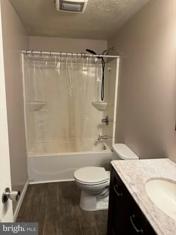 a bathroom with a granite countertop bathtub shower sink vanity and toilet