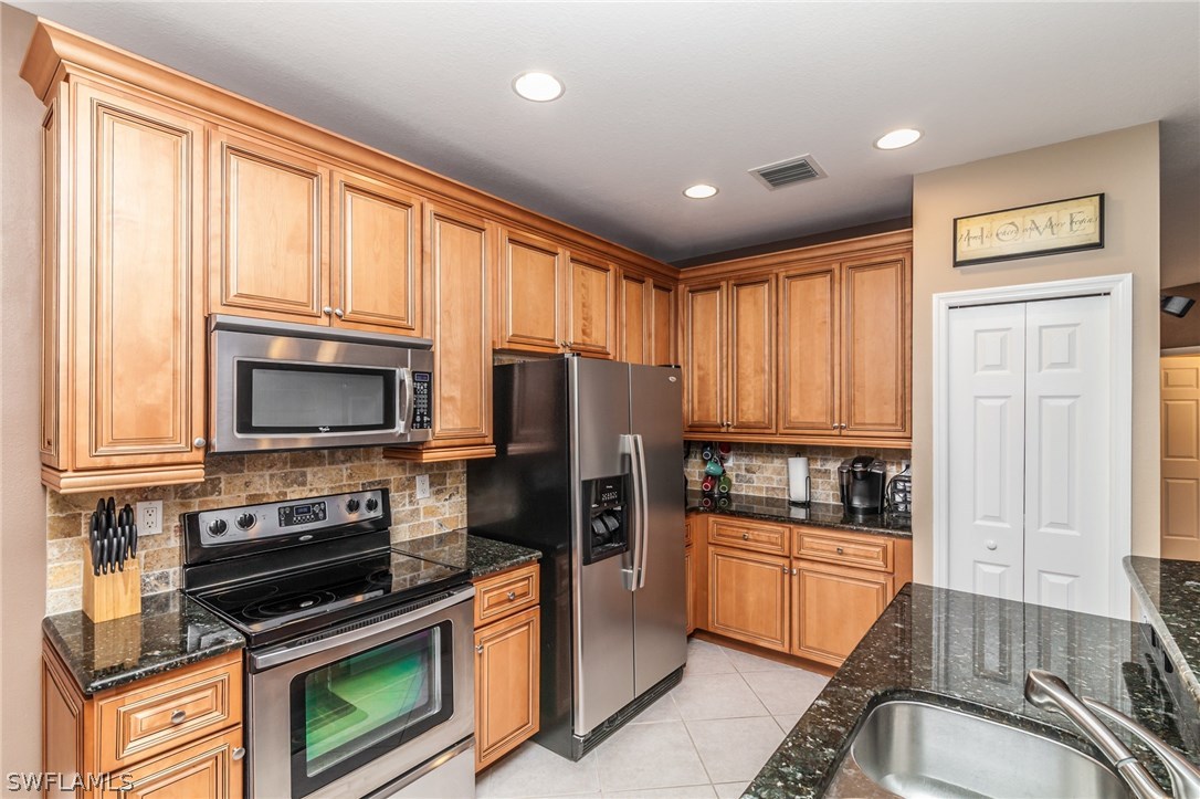 3968 Cherrybrook Loop Fort Myers, FL 33966 - Photo 5 of 16 a kitchen with granite countertop a refrigerator and a stove top oven