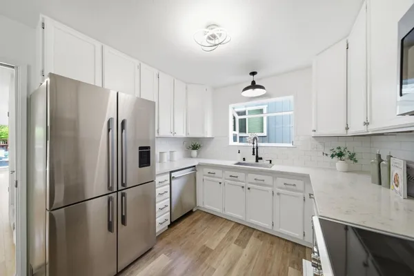 a kitchen with stainless steel appliances granite countertop white cabinets a sink a stove and a microwave
