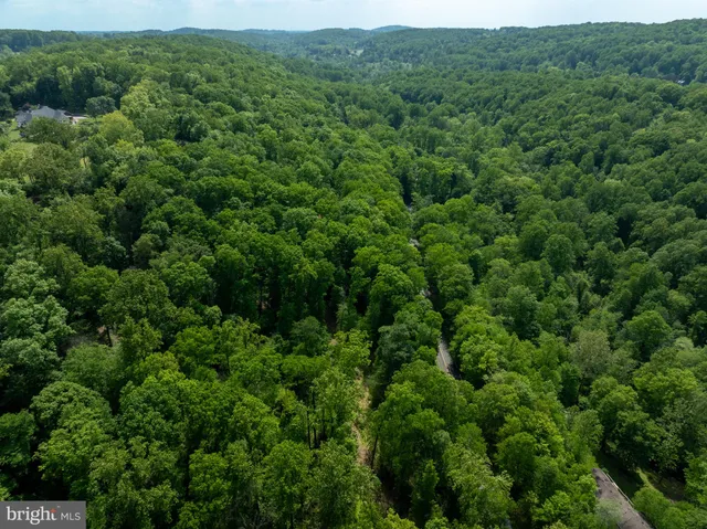 an aerial view of residential house with outdoor space and trees all around