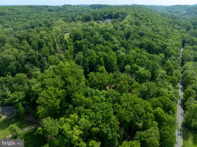 an aerial view of residential house with outdoor space and trees all around