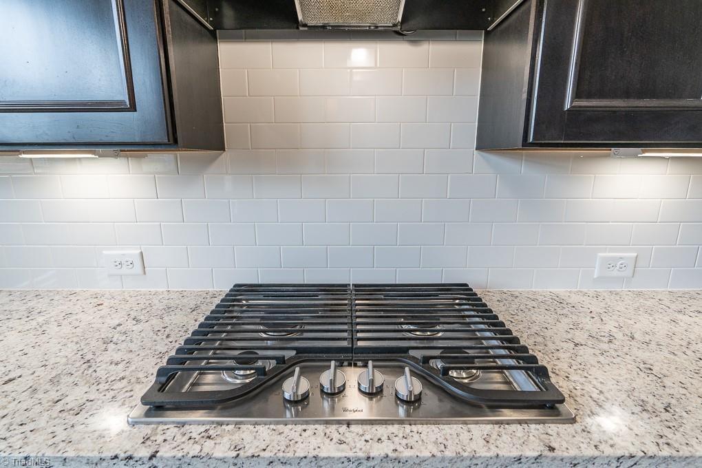 8200 Brotherstwo Road Colfax, NC 27235 - Photo 14 of 50 Stainless appliances, kitchen island, exposed beams, recessed lighting, abundant natural light, granite countertops, tile backsplash, gas cooktop, built in microwave and over, and under cabinet lighting. The refrigerator remains.
