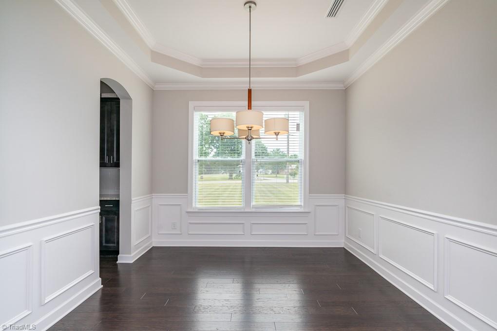 8200 Brotherstwo Road Colfax, NC 27235 - Photo 9 of 50 The dining room features arched door ways, chair moulding, tray ceiling, and double window. The doorway to the left leads to huge pantry and butler's pantry.