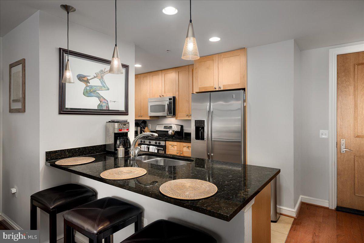 a kitchen with stainless steel appliances granite countertop a sink cabinets and wooden floor