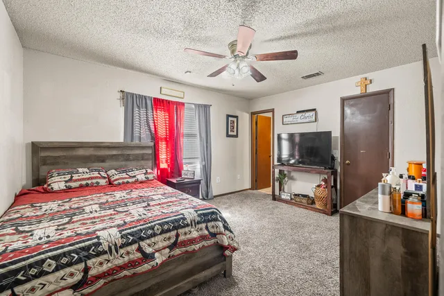 a bedroom with a bed and a flat tv screen on dresser