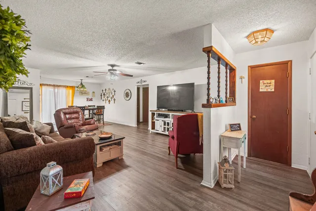 a living room with furniture a flat screen tv and wooden floor