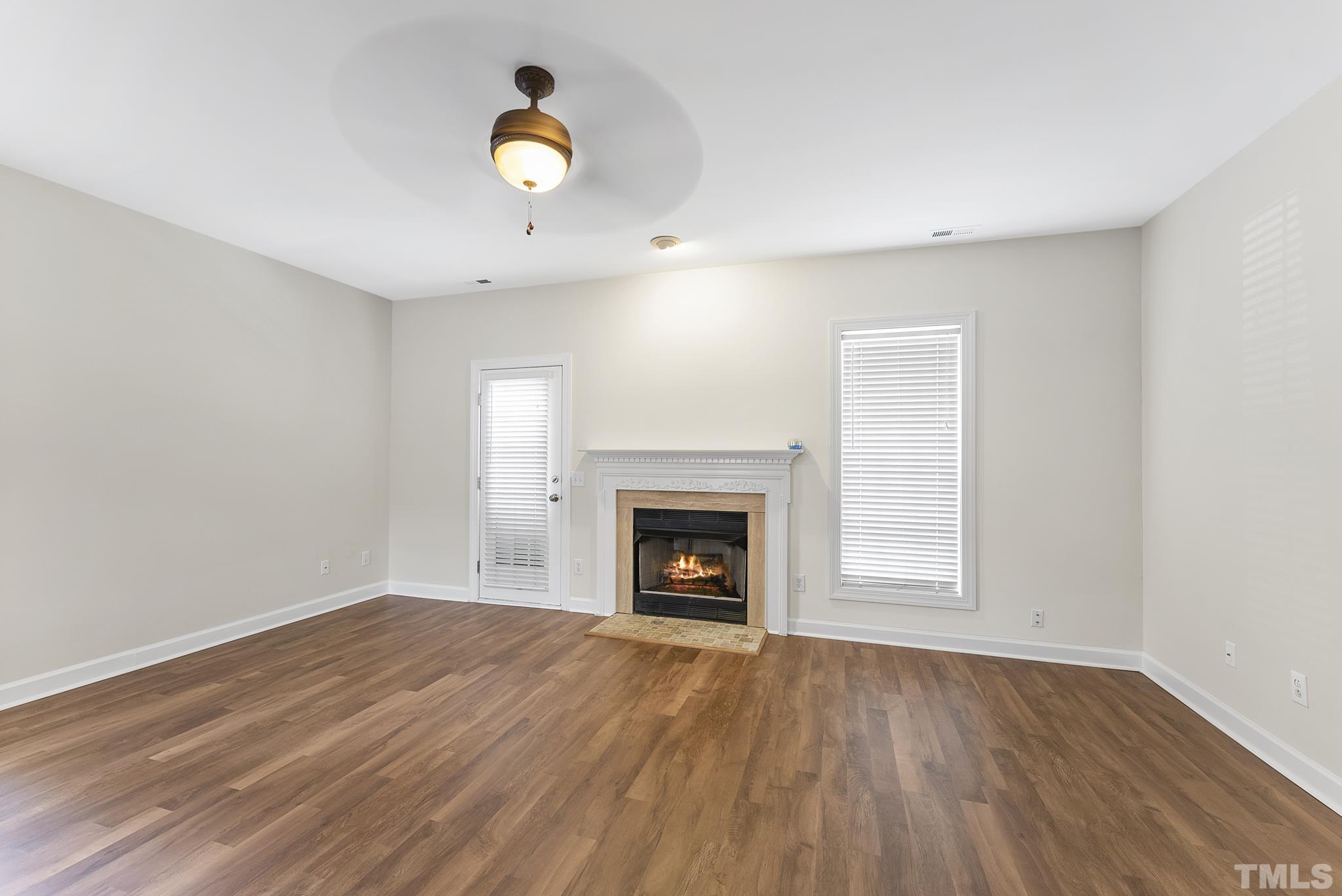 8706 Leeds Forest Lane Raleigh, NC 27615 - Photo 16 of 22 an empty room with wooden floor fireplace and window