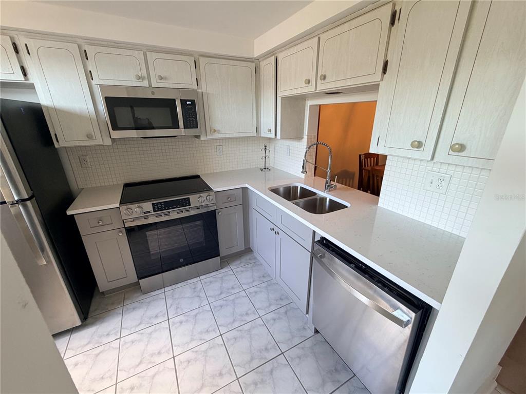 4446 Rustic Drive, Unit E New Port Richey, FL 34652 - Photo 5 of 12 a kitchen with a sink stove and microwave