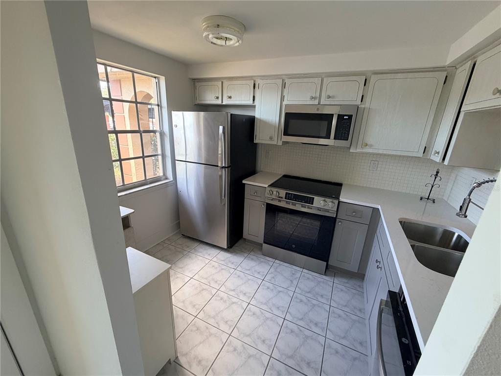 4446 Rustic Drive, Unit E New Port Richey, FL 34652 - Photo 6 of 12 a kitchen with granite countertop a refrigerator and a stove