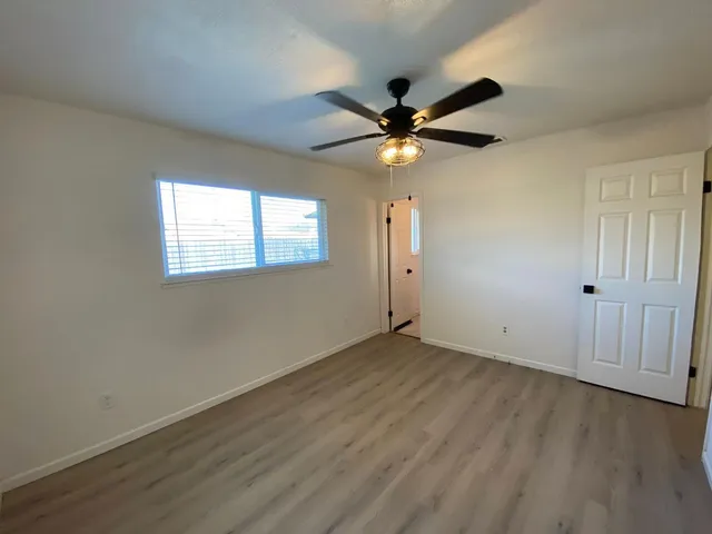 an empty room with wooden floor fan and windows