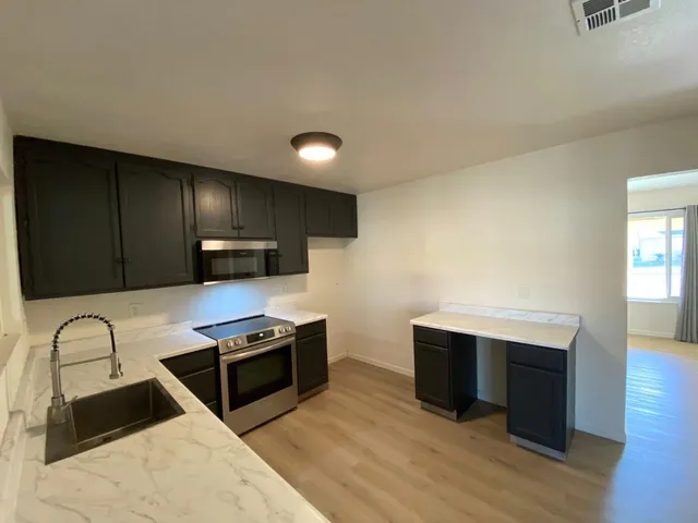 a kitchen with stainless steel appliances granite countertop a stove a sink and a microwave