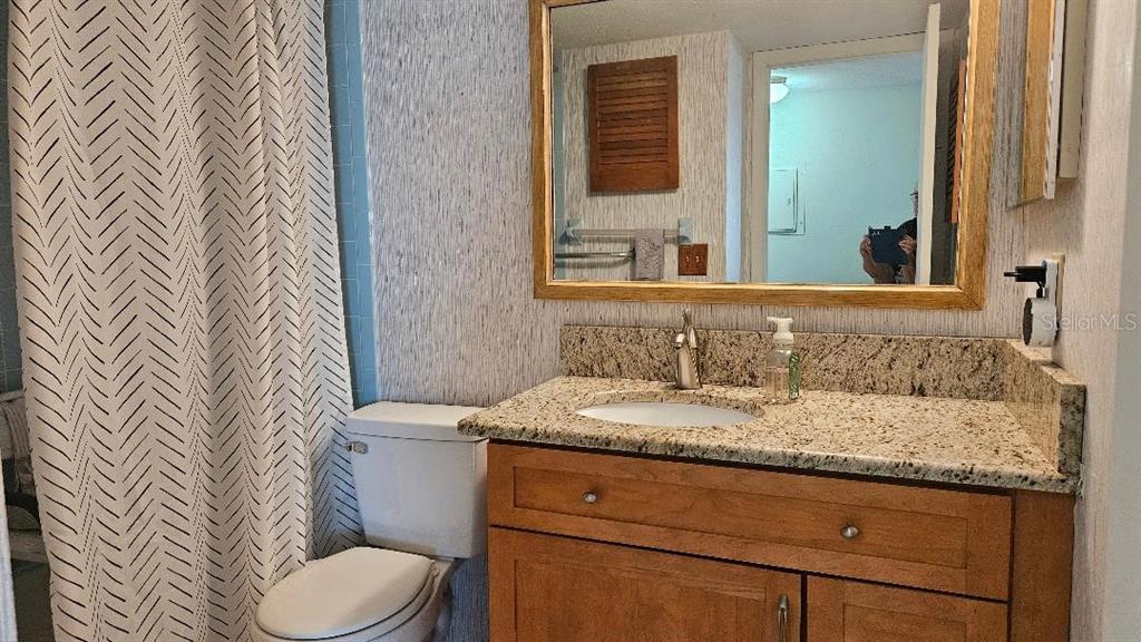 4600 98th Way North, Unit 210 St. Petersburg, FL 33708 - Photo 20 of 33 a bathroom with a granite countertop sink toilet and mirror