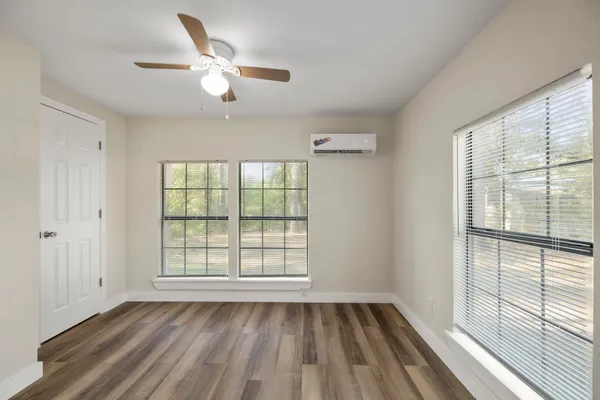 a view of an empty room with a window and wooden floor