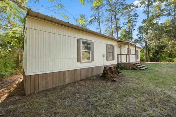 a backyard of a house with wooden fence and a large tree