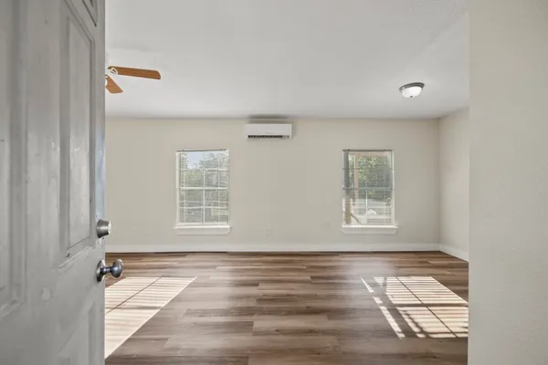 a view of an empty room with wooden floor and a window