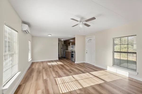 a view of empty room with wooden floor and fan