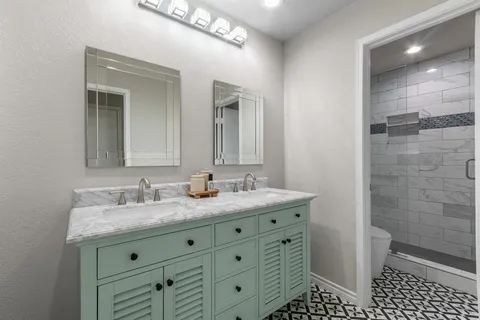 a bathroom with a granite countertop sink a mirror and a shower