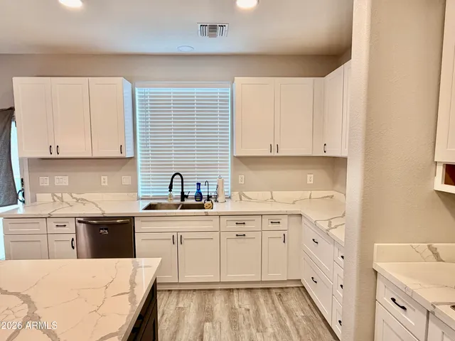 a kitchen with a sink dishwasher stove and white cabinets