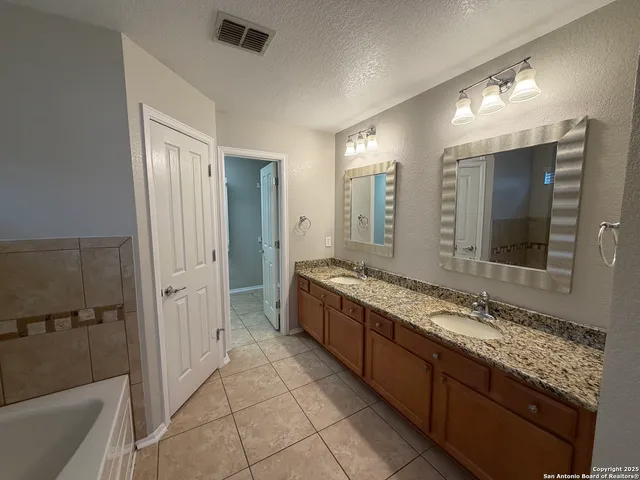 a bathroom with a granite countertop tub sink and mirror