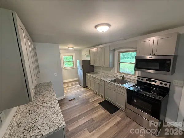 a kitchen with granite countertop a stove a sink and a refrigerator