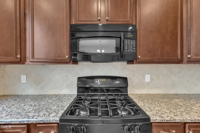 a kitchen with granite countertop a stove and a microwave