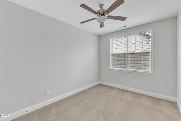 an empty room with a window and a fan