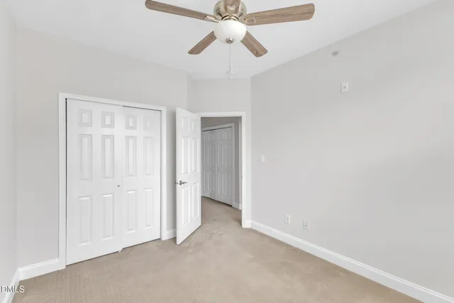an empty room with a chandelier fan and closet