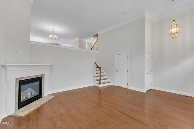 a view of an empty room with wooden floor and a fireplace