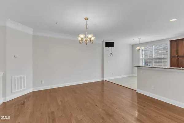 an empty room with wooden floor chandelier and windows